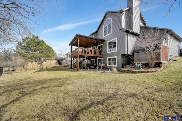 back of property featuring a wooden deck, a yard, a chimney, and fence