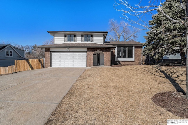 tri-level home with fence, driveway, roof with shingles, a garage, and brick siding