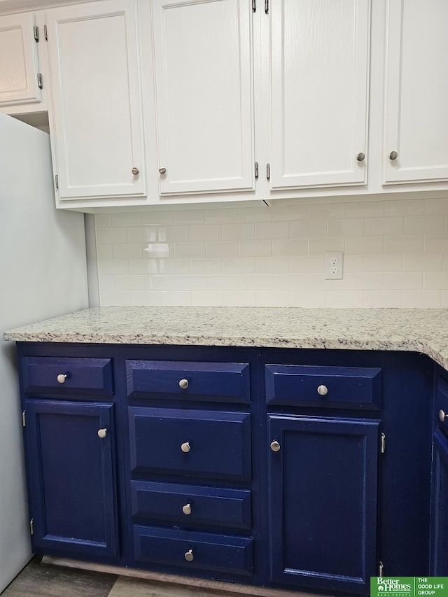 details with backsplash, blue cabinetry, and white cabinets