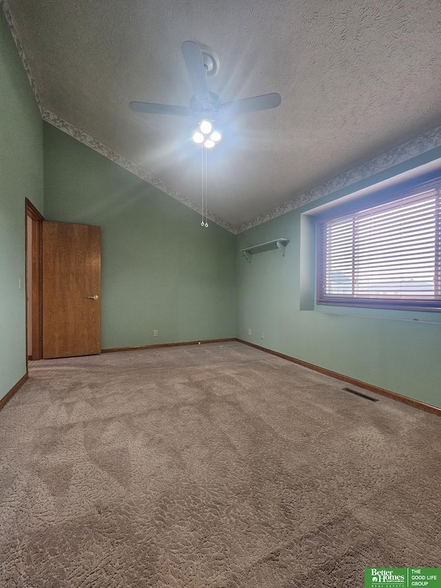 spare room with a ceiling fan, visible vents, baseboards, carpet floors, and vaulted ceiling