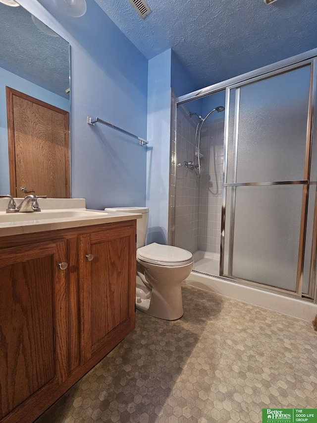 bathroom featuring vanity, visible vents, a stall shower, a textured ceiling, and toilet