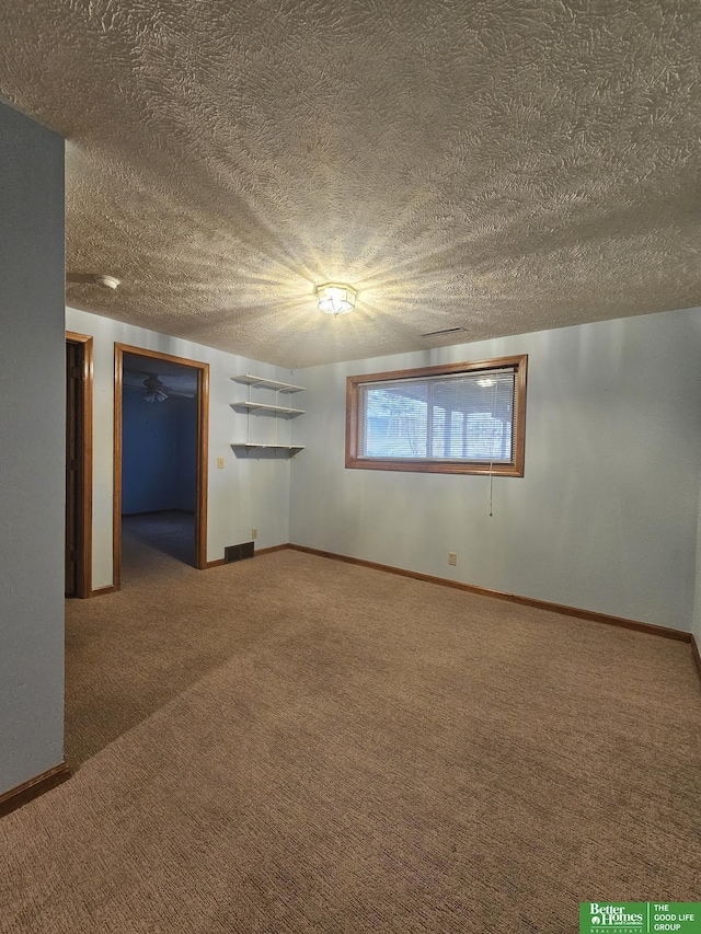 carpeted spare room with visible vents, a textured ceiling, and baseboards