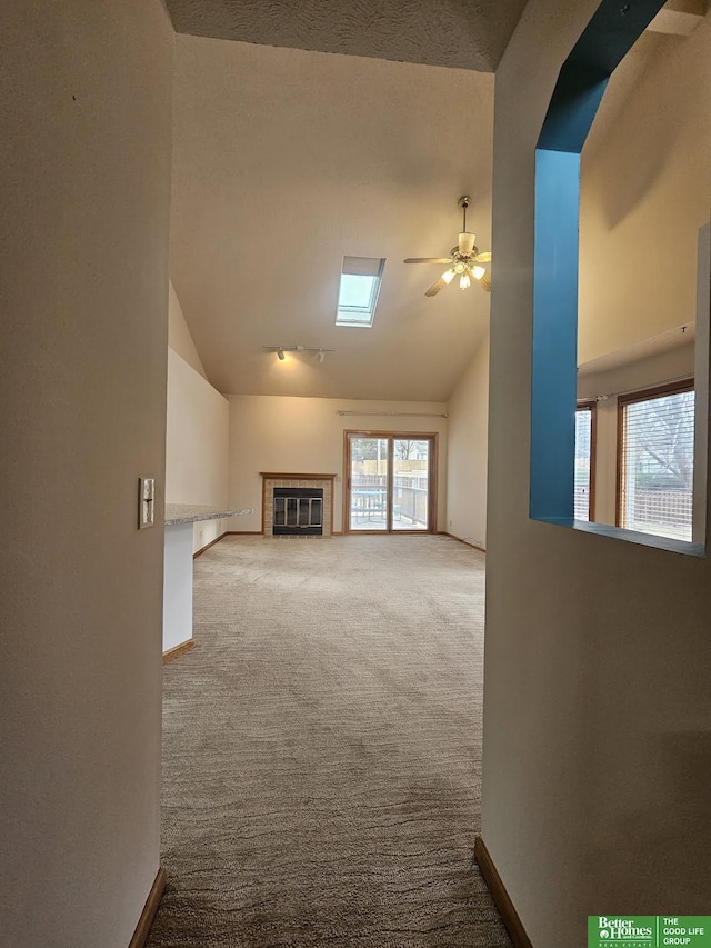 unfurnished living room with carpet flooring, a fireplace, baseboards, and ceiling fan