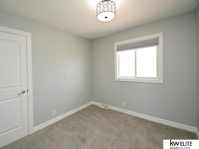 carpeted spare room featuring visible vents and baseboards