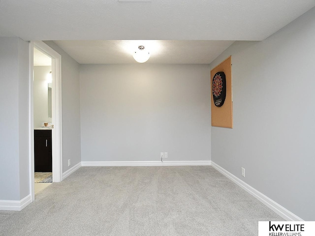 unfurnished room featuring baseboards, light colored carpet, and a textured ceiling