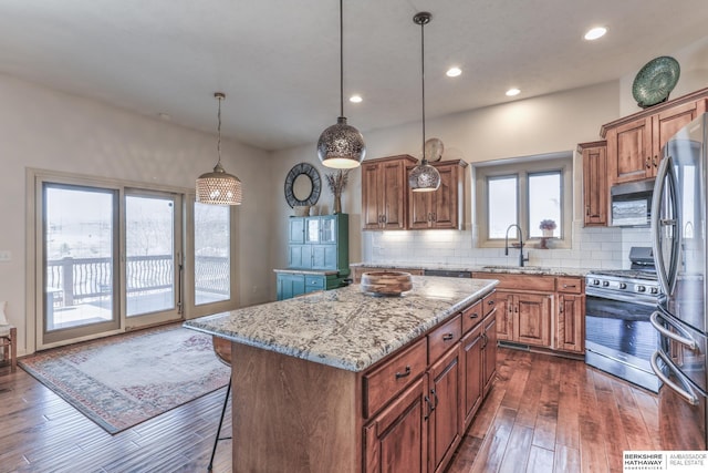 kitchen with a sink, tasteful backsplash, appliances with stainless steel finishes, brown cabinetry, and light stone countertops