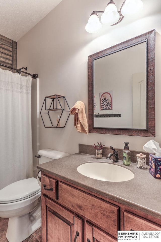 full bathroom featuring vanity, curtained shower, toilet, and a textured ceiling