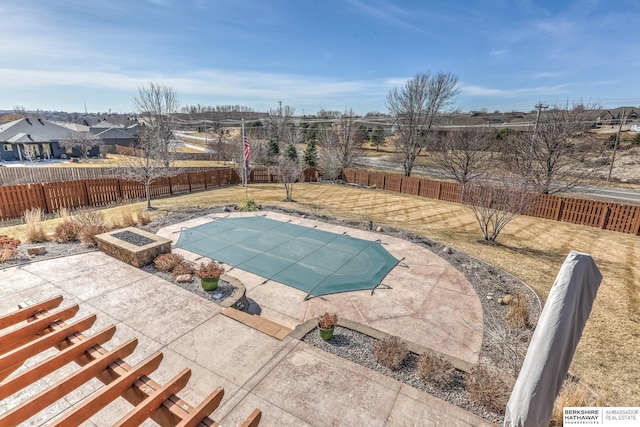 view of swimming pool featuring a patio, a yard, a fire pit, and a fenced backyard