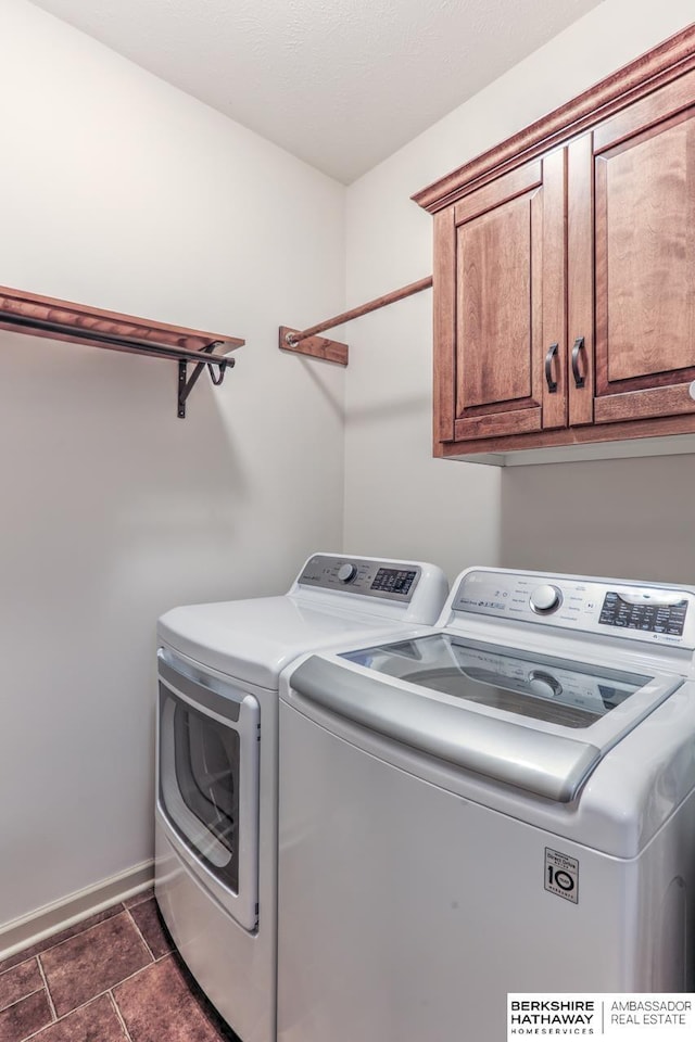 clothes washing area featuring cabinet space, washing machine and dryer, and baseboards