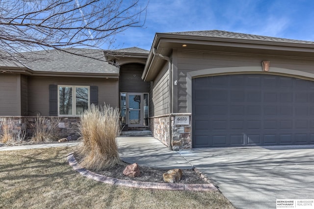 view of front of home featuring an attached garage, roof with shingles, and driveway