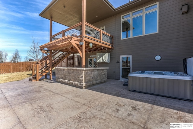 view of patio with a wooden deck, a hot tub, stairs, and fence