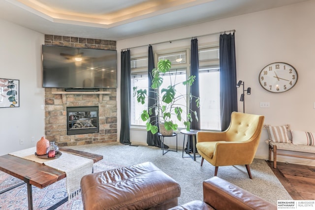 living room with a tray ceiling and a fireplace