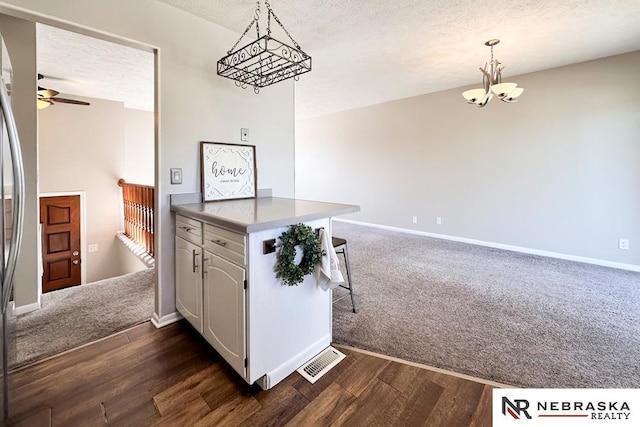 kitchen featuring baseboards, dark wood finished floors, ceiling fan with notable chandelier, a peninsula, and a textured ceiling