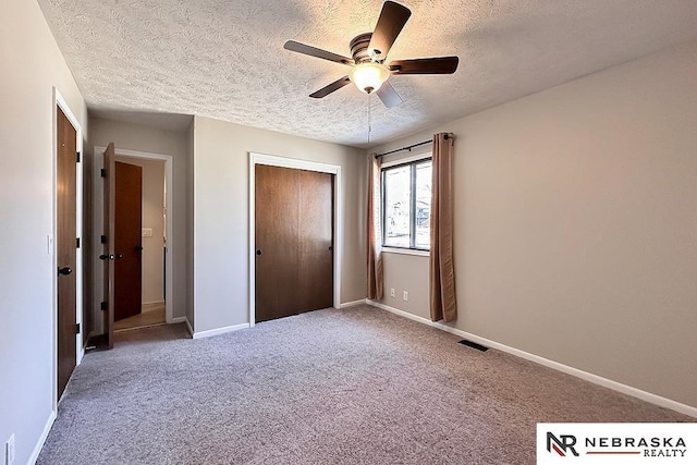 unfurnished bedroom featuring visible vents, a textured ceiling, a closet, carpet floors, and baseboards