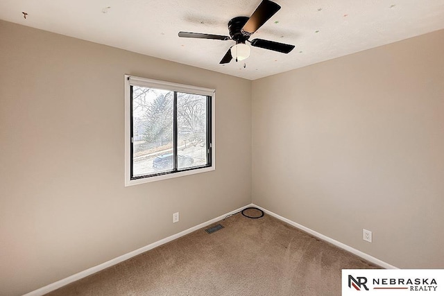 carpeted spare room featuring visible vents, baseboards, and ceiling fan