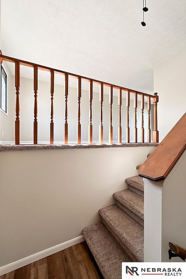 staircase featuring wood finished floors and baseboards