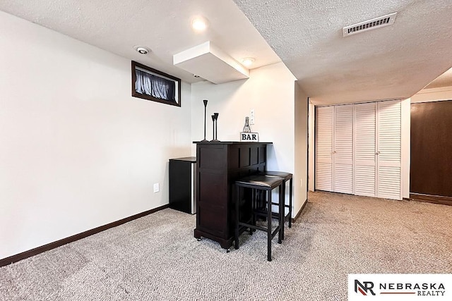 interior space featuring visible vents, baseboards, carpet, and a textured ceiling