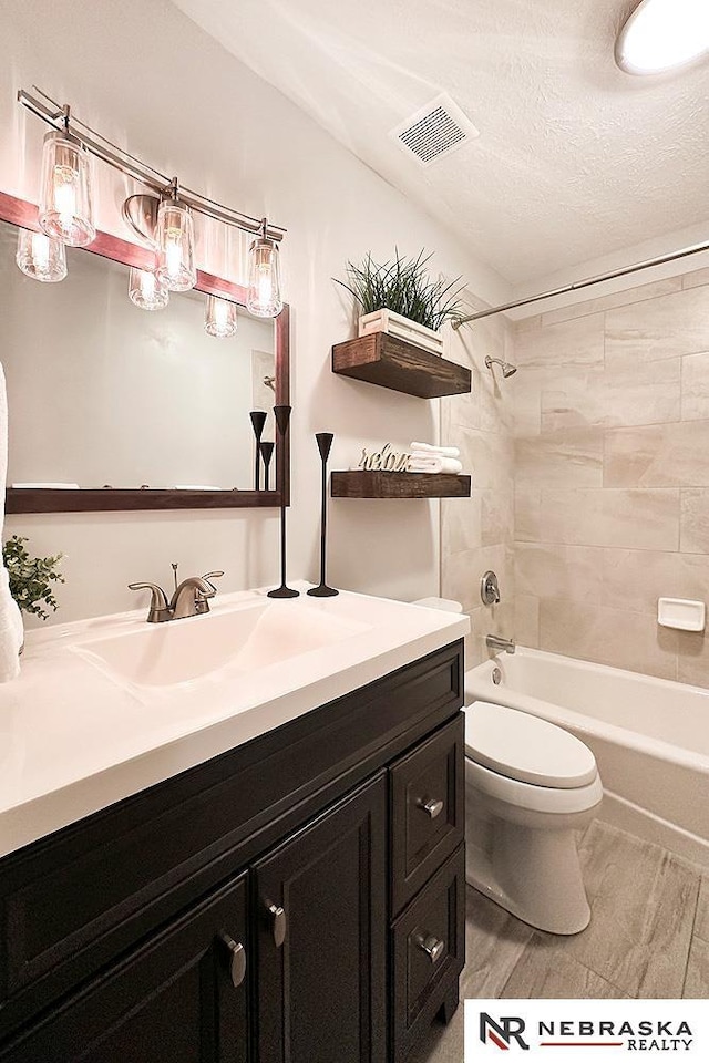 bathroom featuring visible vents, toilet, a textured ceiling, shower / washtub combination, and vanity