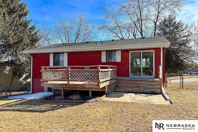 rear view of house with a deck, a yard, and fence