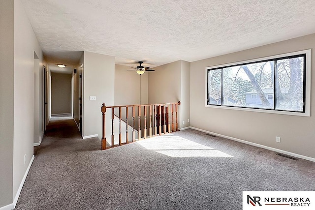 carpeted spare room featuring baseboards, visible vents, and a textured ceiling