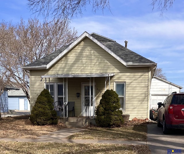 bungalow-style home with a porch, concrete driveway, a garage, and roof with shingles