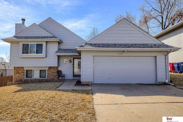 tri-level home with driveway, a shingled roof, a garage, brick siding, and a chimney