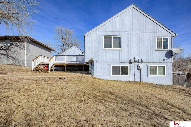 back of property with fence, a lawn, and a wooden deck