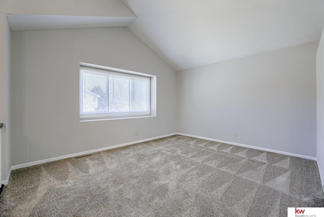 carpeted spare room with visible vents, baseboards, and lofted ceiling