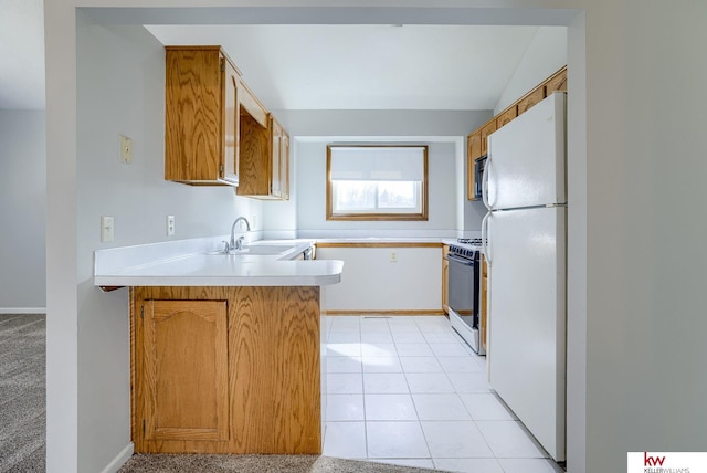 kitchen featuring light countertops, light tile patterned floors, a peninsula, white appliances, and a sink