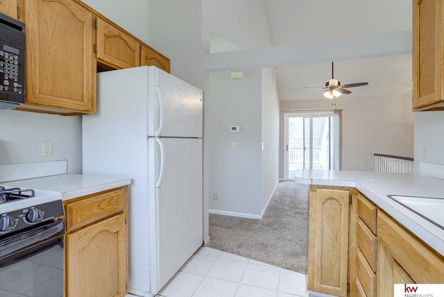 kitchen featuring black microwave, light colored carpet, gas range, light countertops, and freestanding refrigerator