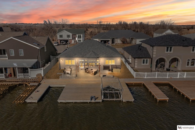 aerial view at dusk featuring a residential view and a water view