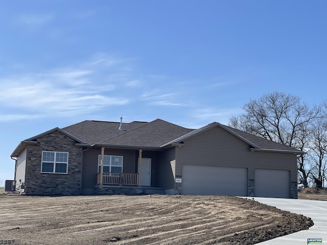 single story home with central AC unit, roof with shingles, a porch, an attached garage, and stone siding