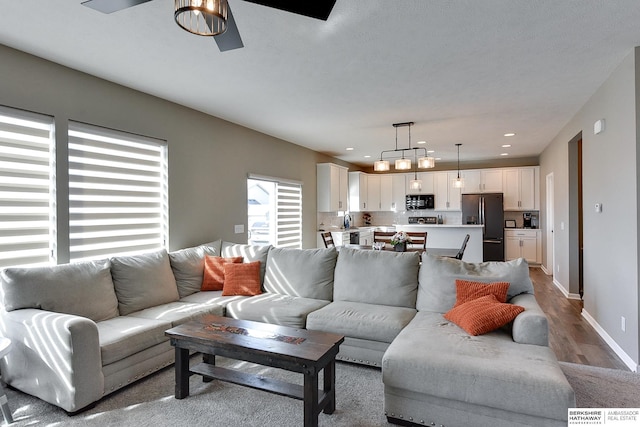 living area with recessed lighting, wood finished floors, baseboards, and ceiling fan