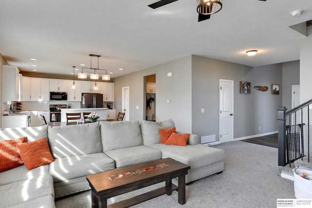 living room featuring visible vents, baseboards, stairway, light colored carpet, and recessed lighting