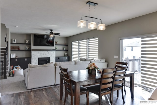 dining space featuring ceiling fan, plenty of natural light, dark wood-style floors, and a fireplace