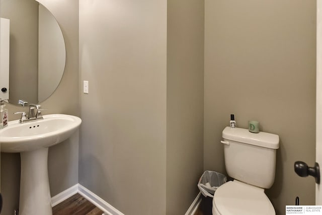 bathroom featuring a sink, baseboards, toilet, and wood finished floors