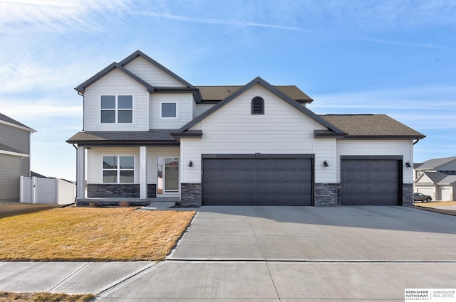 craftsman inspired home featuring fence, an attached garage, a front lawn, concrete driveway, and stone siding