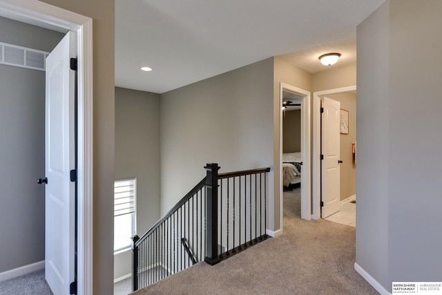 hallway featuring visible vents, baseboards, and carpet flooring