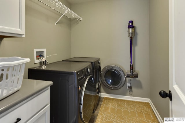 washroom featuring cabinet space, baseboards, and washer and clothes dryer