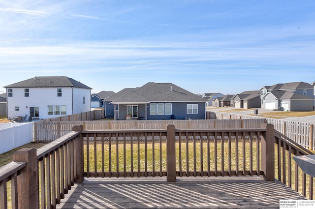 wooden terrace featuring a fenced backyard, a residential view, and a yard