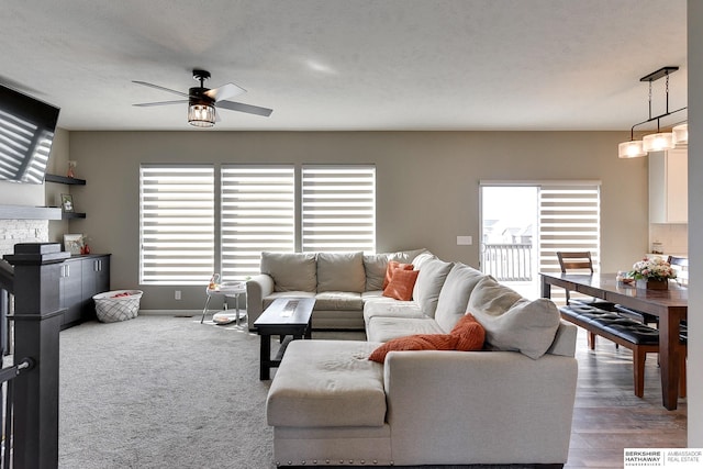 living room with a fireplace, baseboards, and ceiling fan