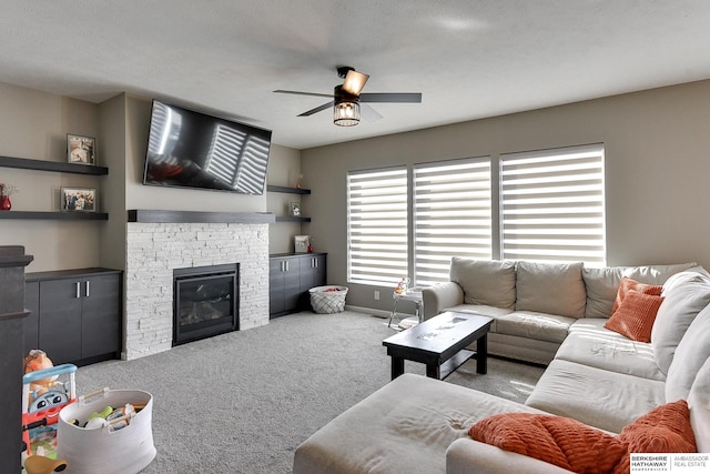 carpeted living room with a textured ceiling, a fireplace, baseboards, and ceiling fan