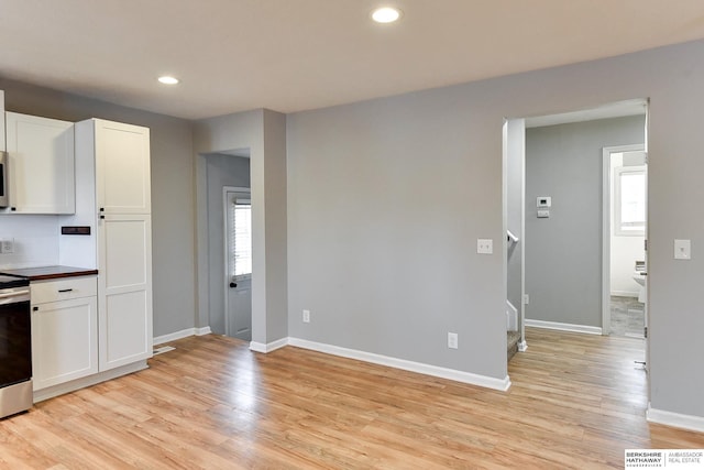 kitchen with white cabinetry, light wood-style floors, and baseboards