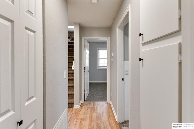 corridor with stairway, visible vents, baseboards, light wood-style flooring, and a barn door