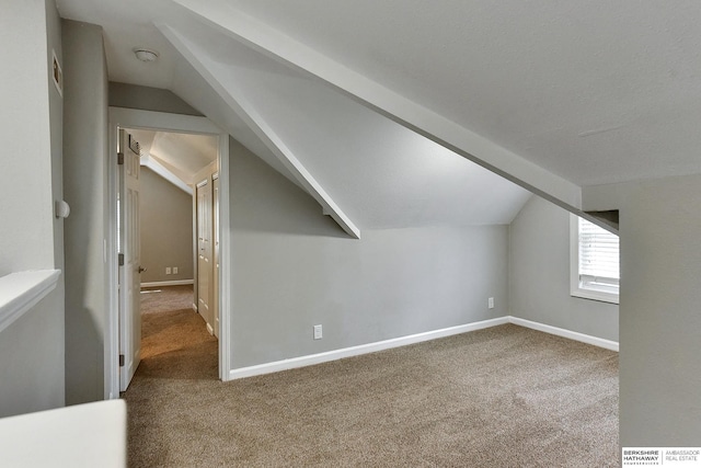 additional living space with lofted ceiling with beams, baseboards, and carpet