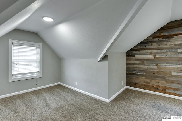 additional living space featuring visible vents, wooden walls, baseboards, vaulted ceiling, and carpet flooring