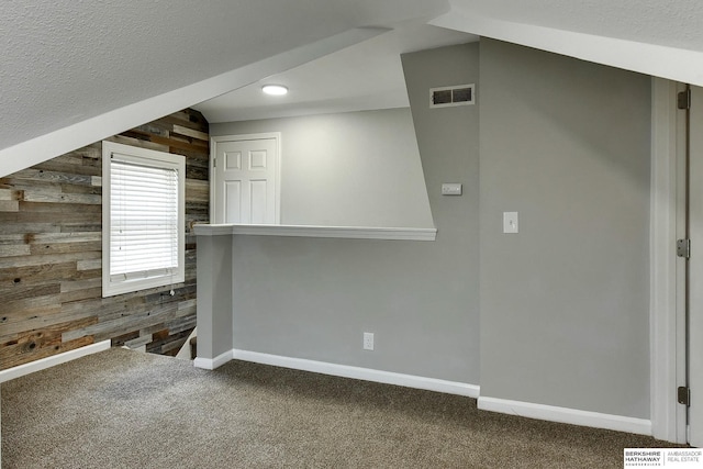 bonus room with wooden walls, baseboards, visible vents, and carpet floors