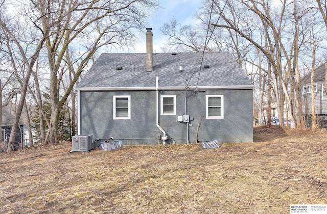 back of property featuring central air condition unit, a chimney, roof with shingles, and stucco siding