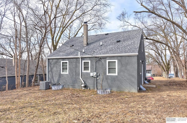 back of property featuring cooling unit, a chimney, roof with shingles, and stucco siding