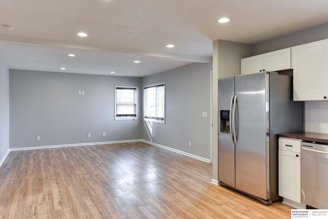 kitchen featuring white cabinets, baseboards, light wood-type flooring, and stainless steel appliances